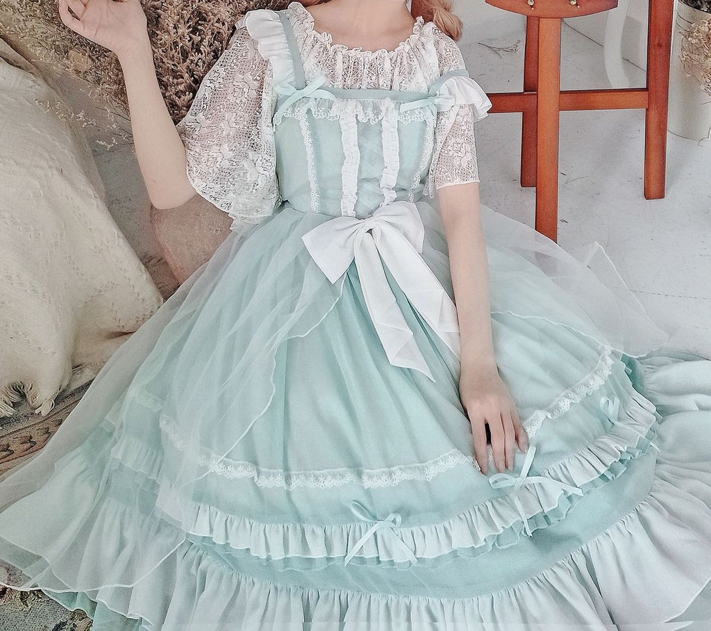 Person wearing a light blue and white dress with ruffles in an indoor setting.