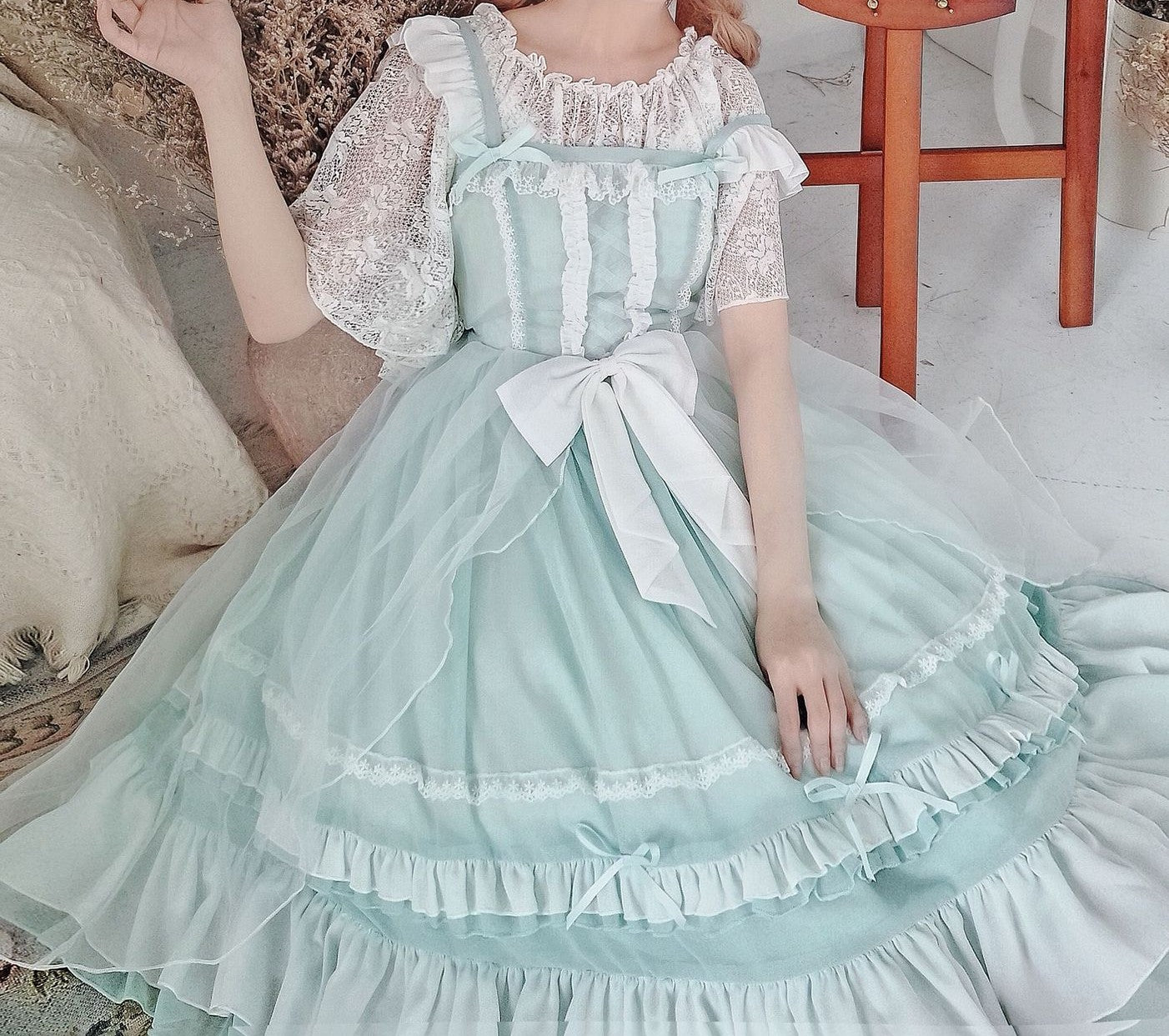 Person wearing a light blue and white dress with ruffles in an indoor setting.