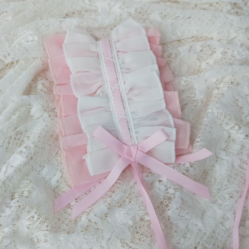 White baby booties with pink ribbons on a textured white background