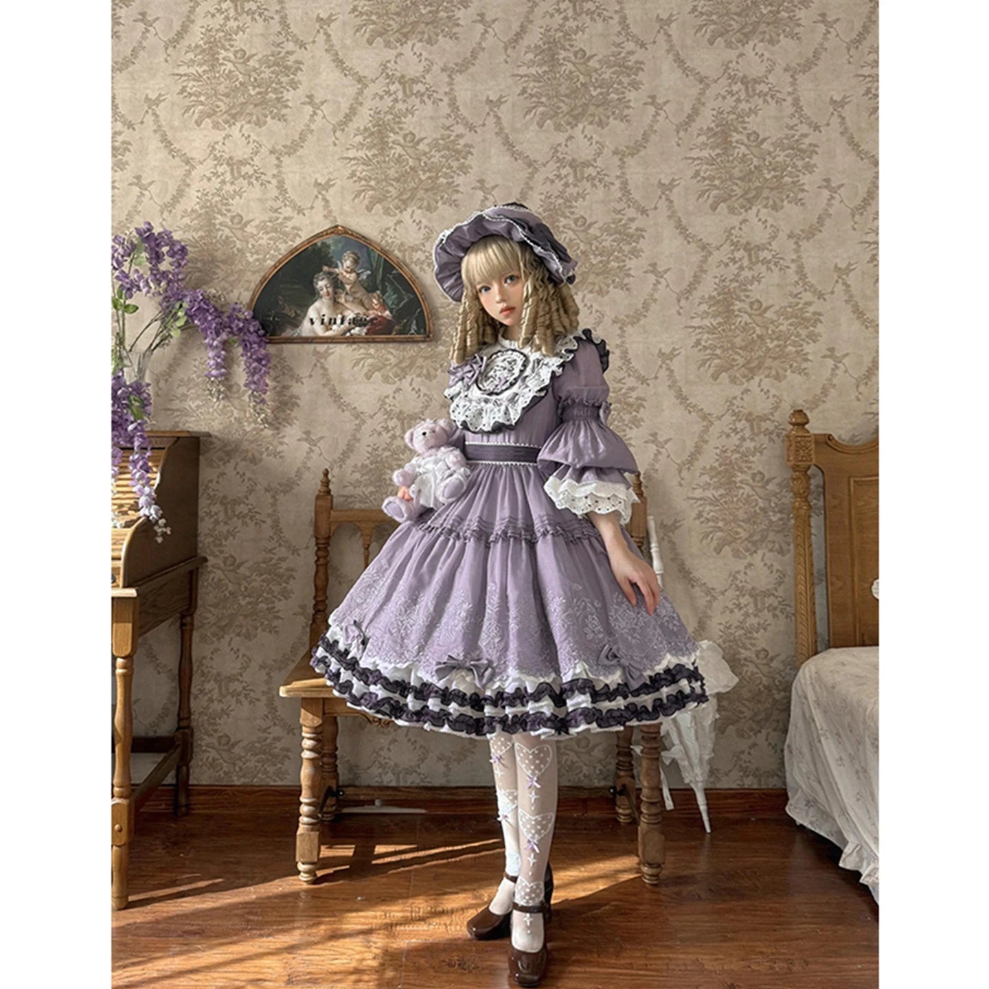 Person in a vintage-style dress standing in a room with decorative wallpaper and furniture.